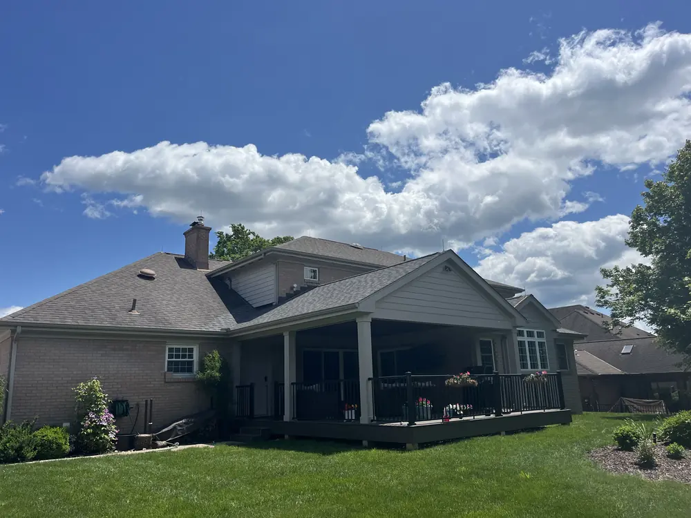 Rear of a brick home with a covered deck and a protected roofline