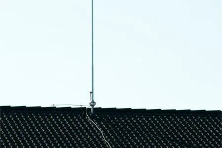 Lightning rod air terminal installed on a shingle roof ridge with concealed conductor cable