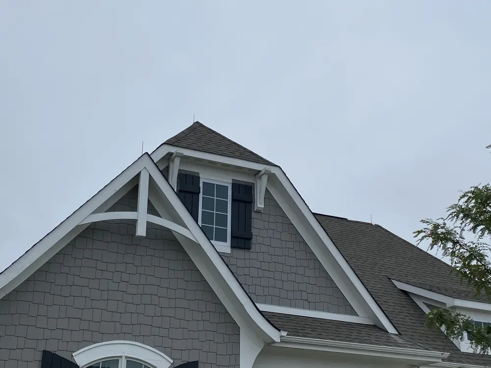 Lightning air terminal at the peak of a shingled gable on a protected home