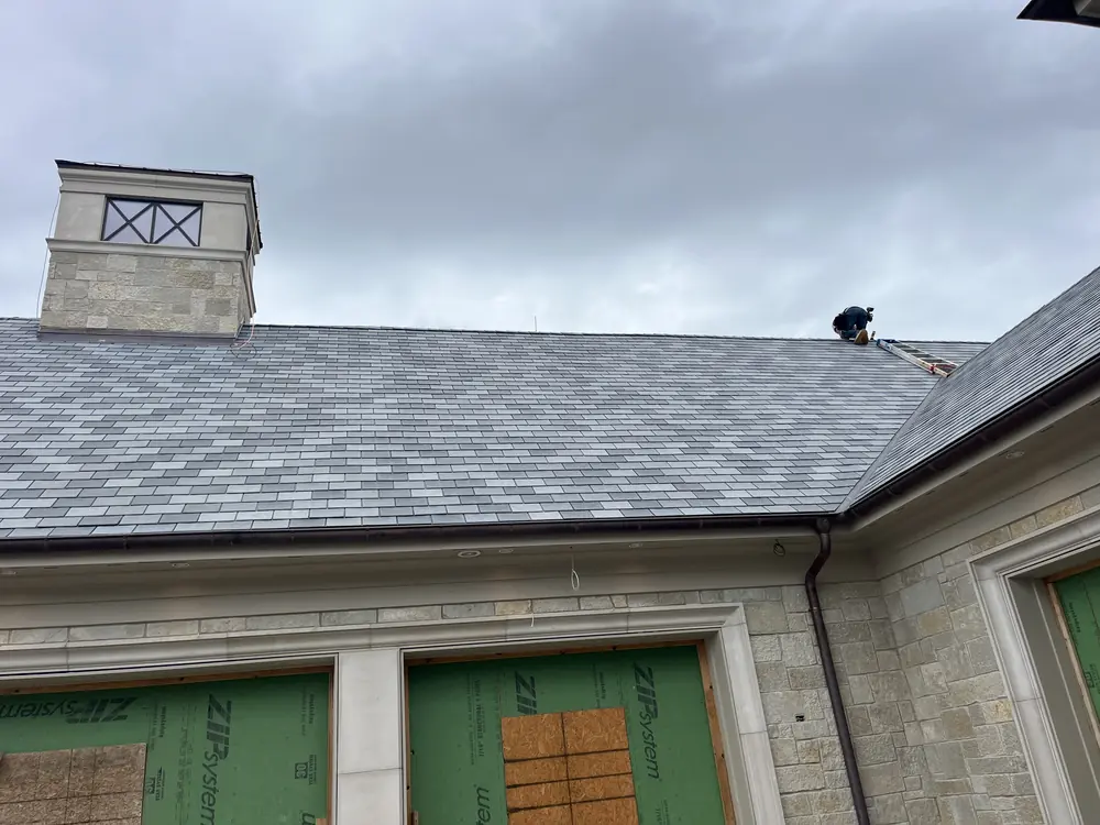 Installer working on a wide slate roof near a stone cupola